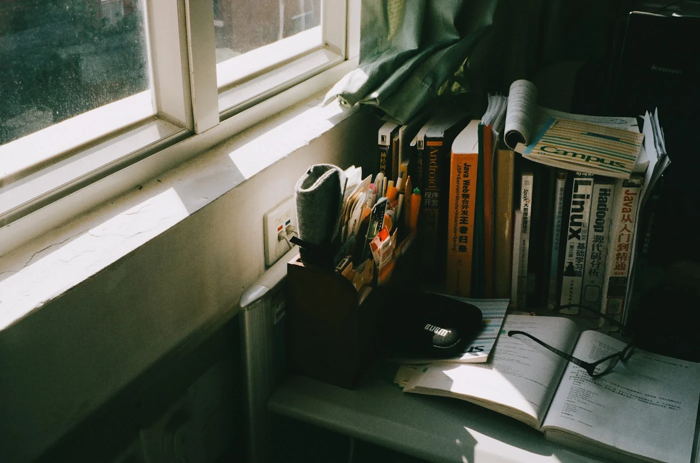 An open notebook and books on a desk in warm window light.